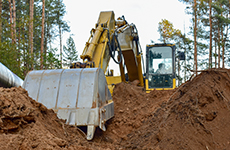 Excavator during earthwork for laying Crude oil and Natural gas pipeline in forest area. Installation of gas and crude oil pipes in ground. Construction of the gas pipes to new LNG plant